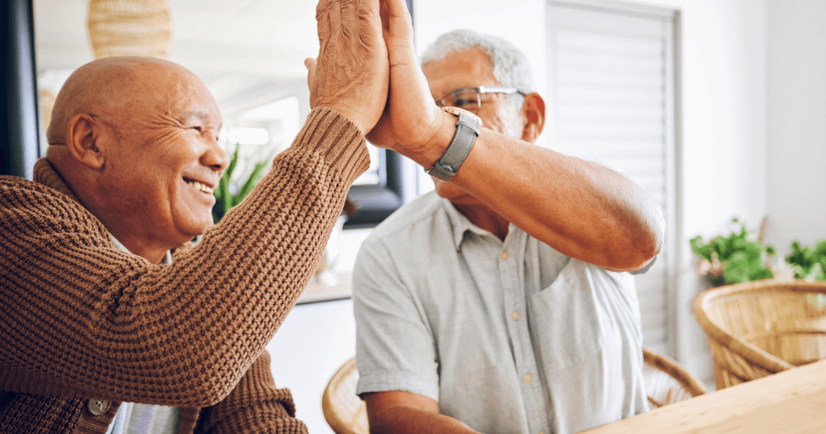 Two senior men giving each other a high five.