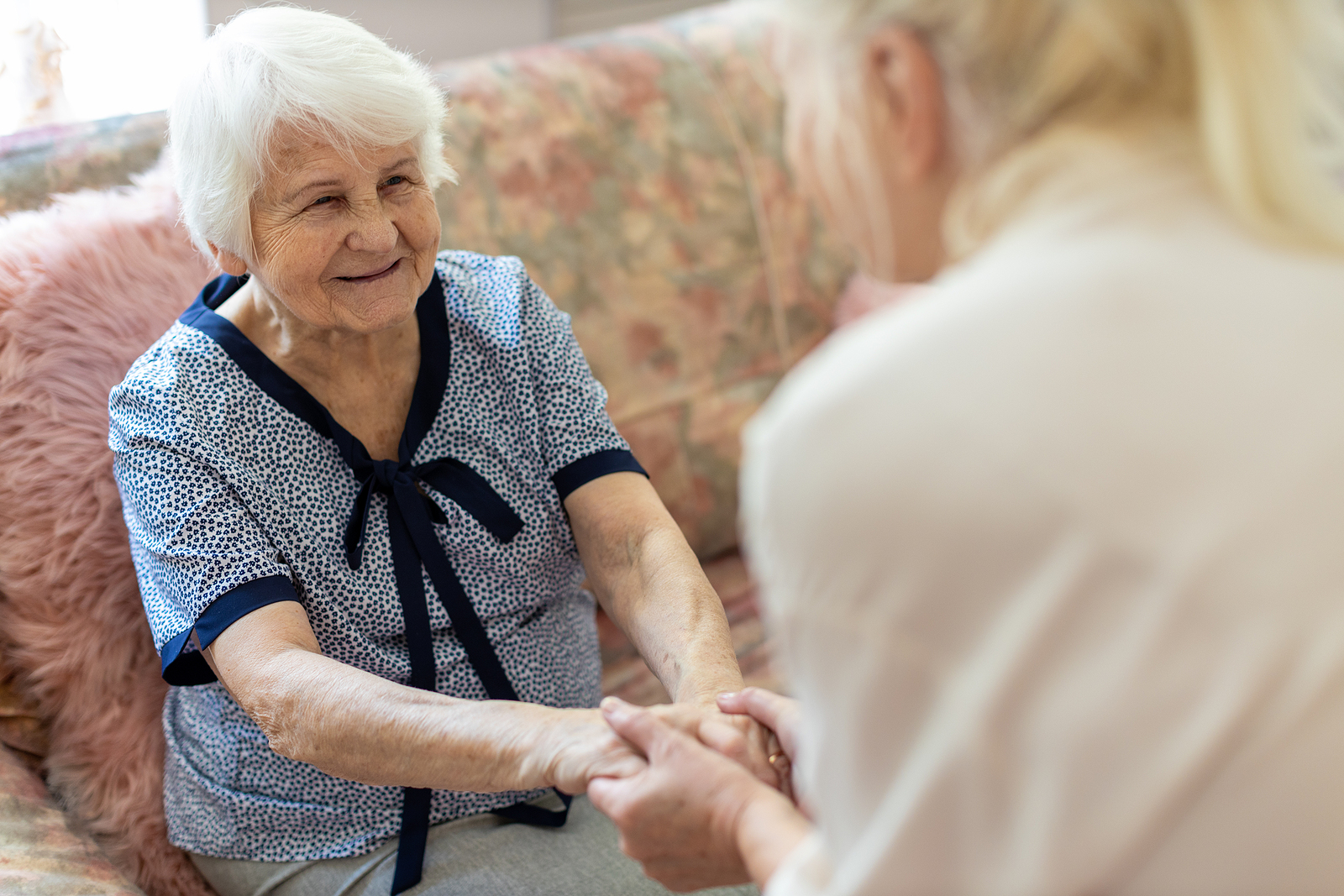 Senior woman holds hands with adult child discussing signs it might be time for assisted living