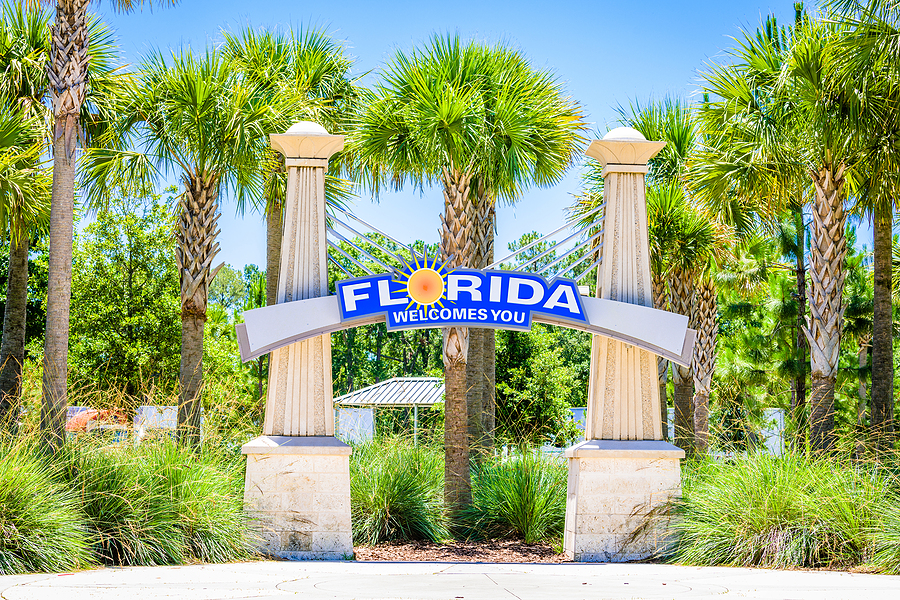 Welcome sign for senior living in Florida with palm trees in background