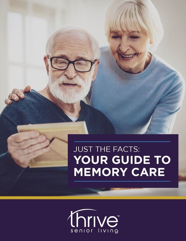 An older man holding a photo frame sits next to a smiling older woman. Text reads: "Just the facts: Your guide to memory care. Thrive Senior Living—caring for every moment.